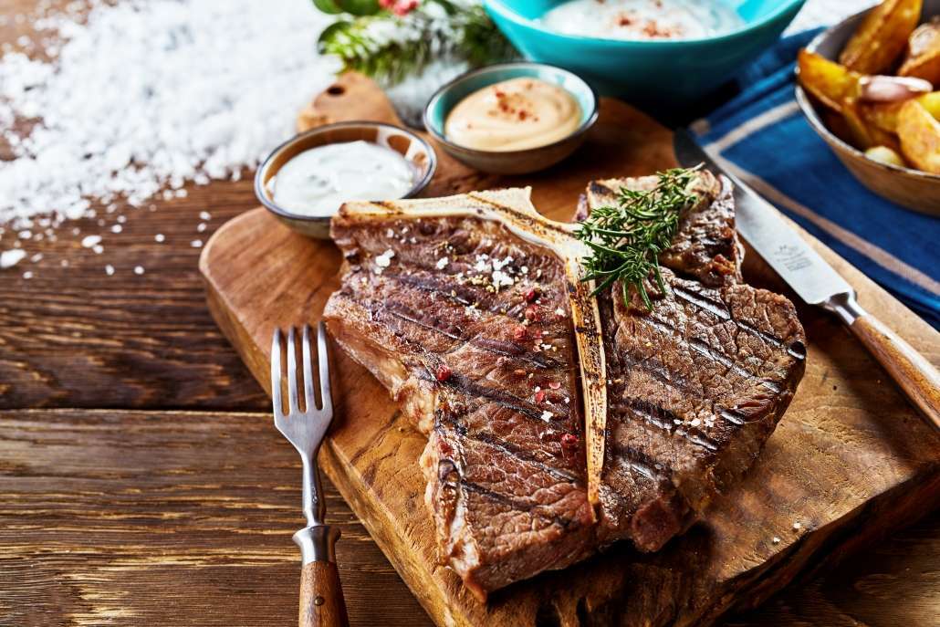 Saftiges gegrilltes T-Bone-Steak auf rustikalem Holzbrett serviert.